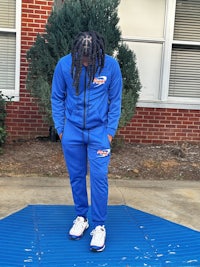 a person in a blue tracksuit standing on a sidewalk