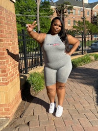 a black woman in a grey romper posing for a photo