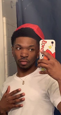 a man in a red hat taking a selfie in a bathroom